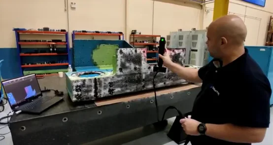 Técnico da Interfag digitalizando uma peça industrial com scanner 3D portátil sobre bancada de desempeno.